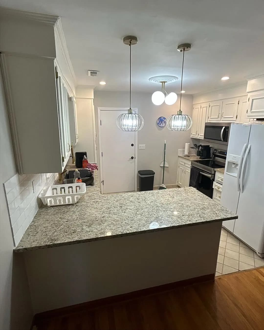 Wide view of completed modern kitchen with pendant lights over peninsula