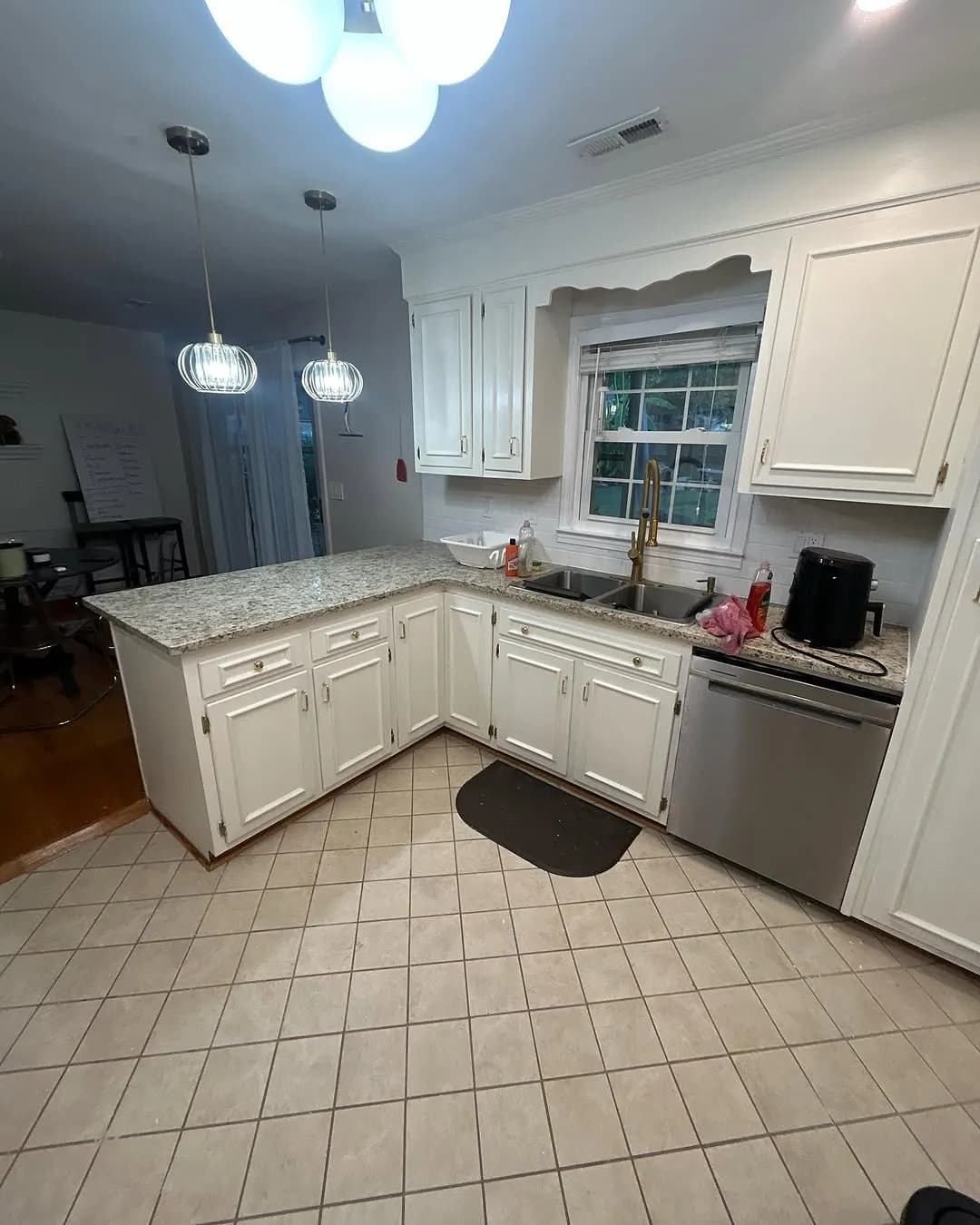 Wide angle of completed L-shaped kitchen with granite countertops and white cabinets