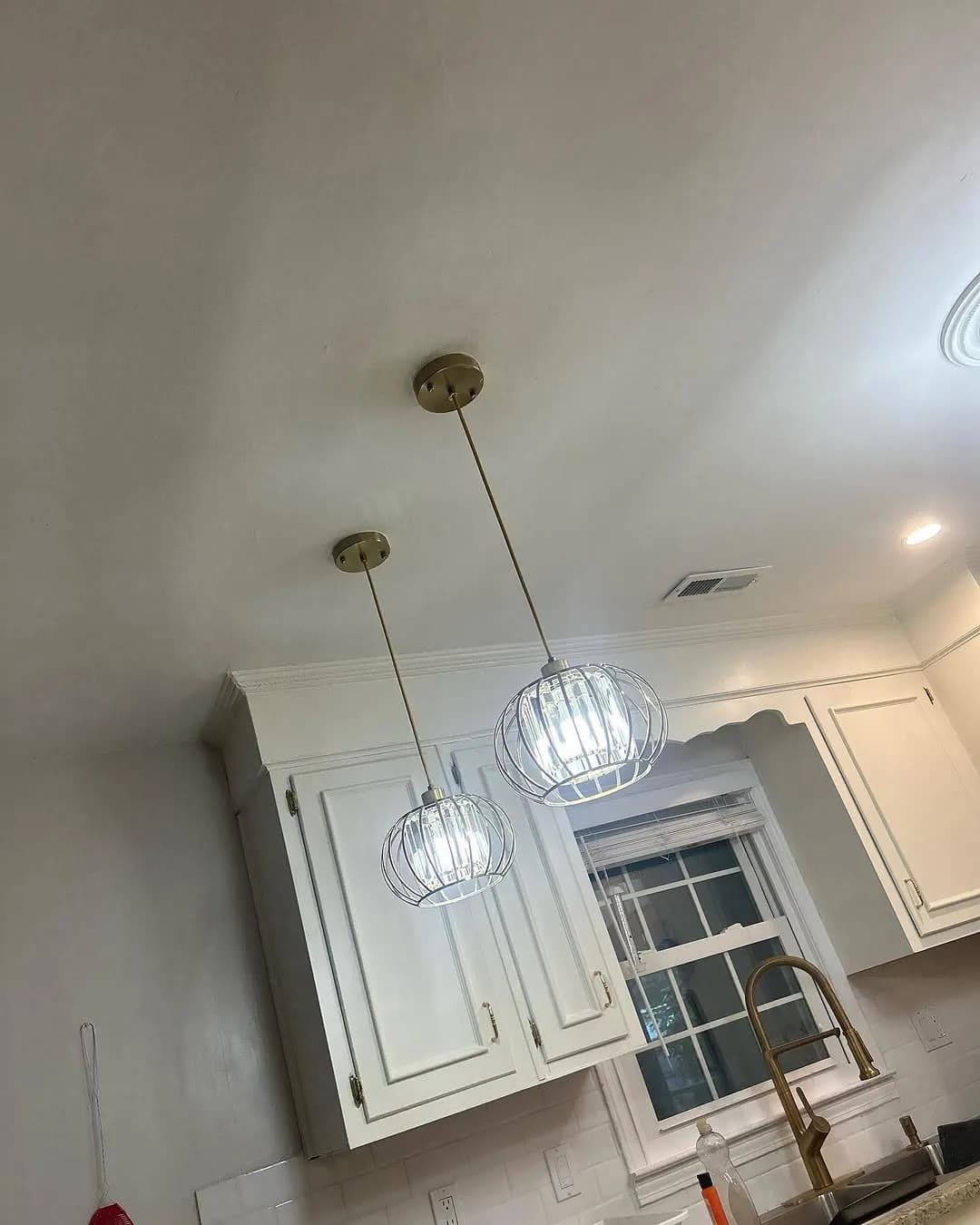Modern open-cage globe pendant lights hanging over kitchen peninsula