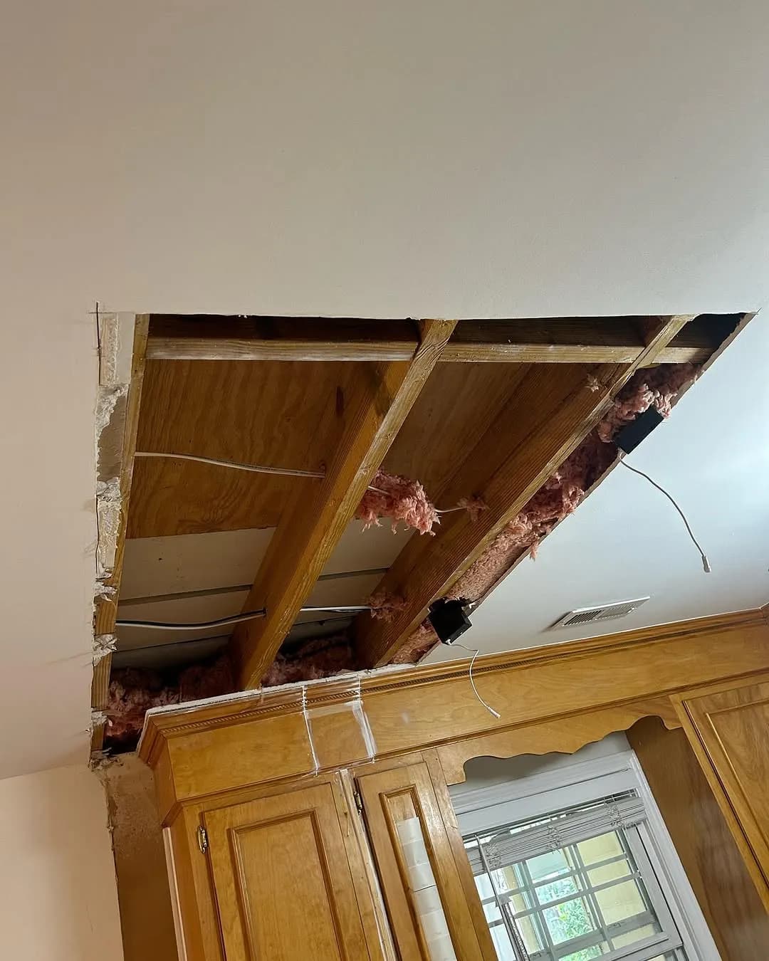 Overhead cabinet removed exposing ceiling joists and old drywall