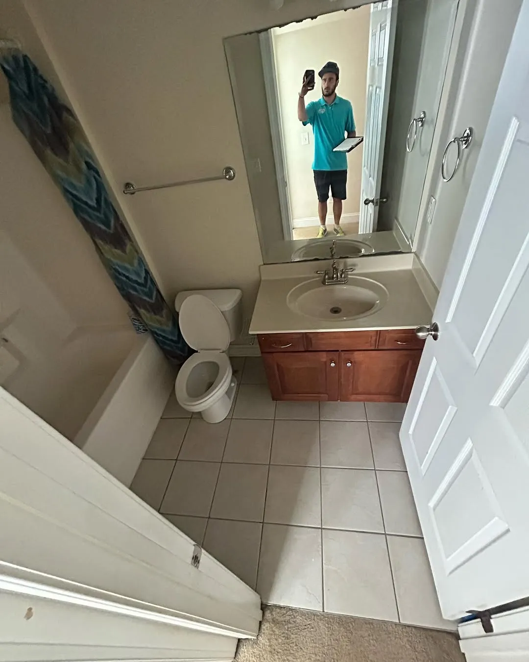 Another angle of the dated bathroom showing vanity mirror and builder-grade fixtures