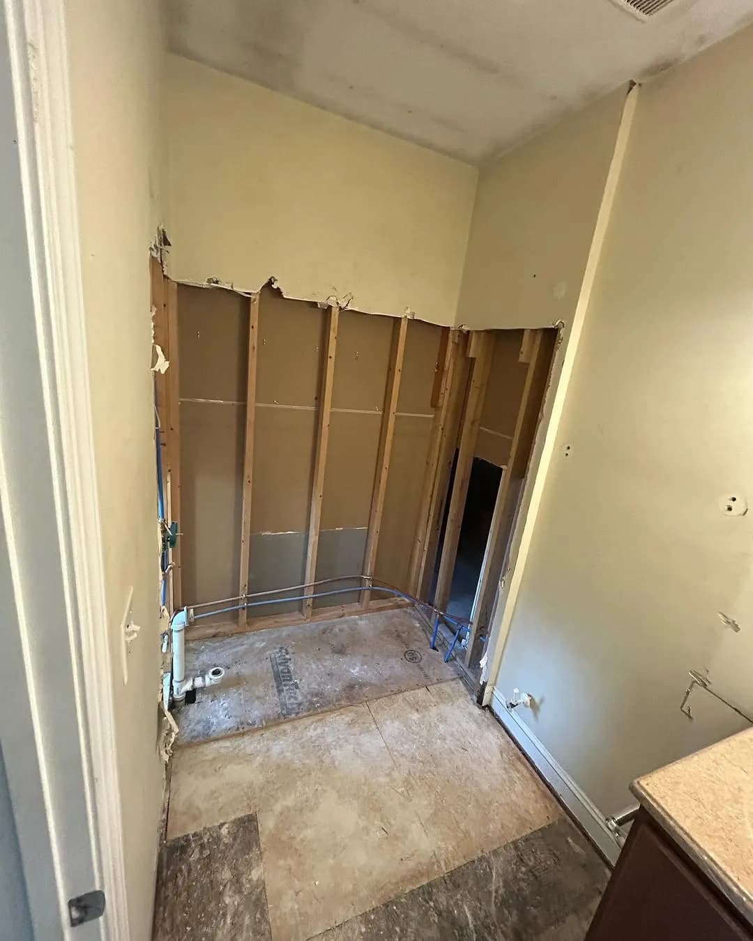 Tub surround stripped to wall studs with exposed framing and plumbing