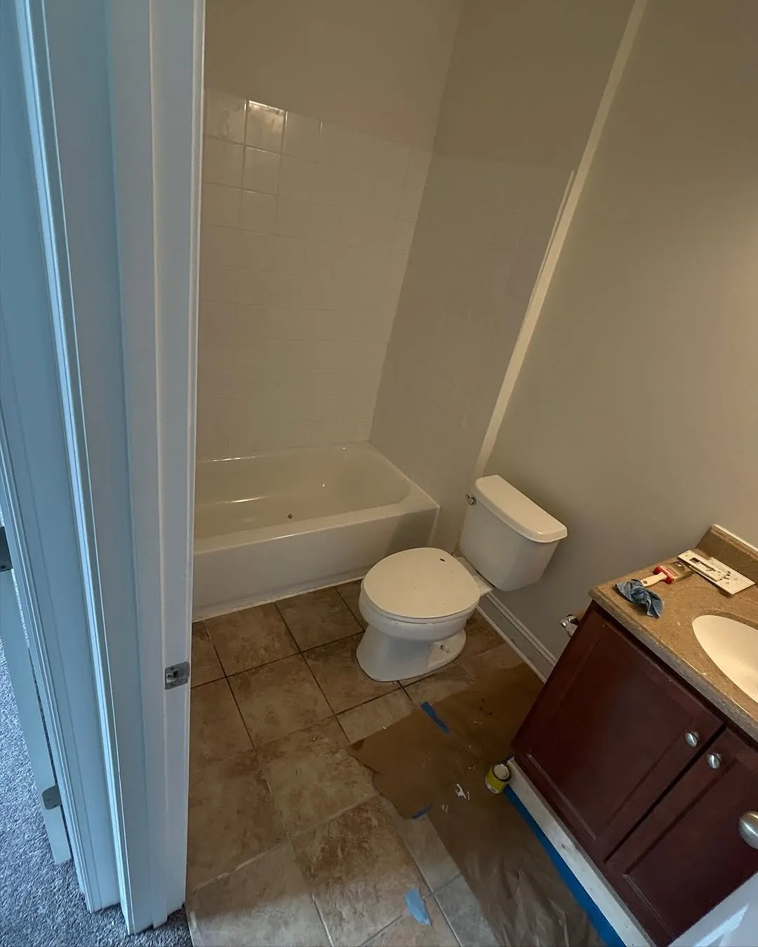 New tile surround installed around tub with new toilet and vanity being set in place